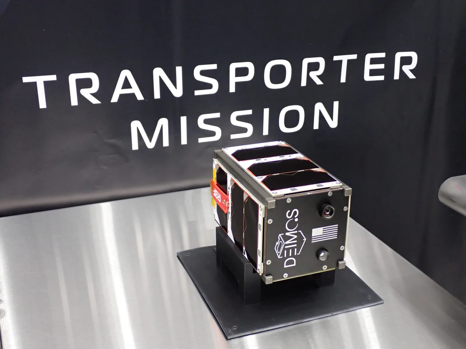 Deimos flight unit in front of the Transporter mission backdrop at the integration facility